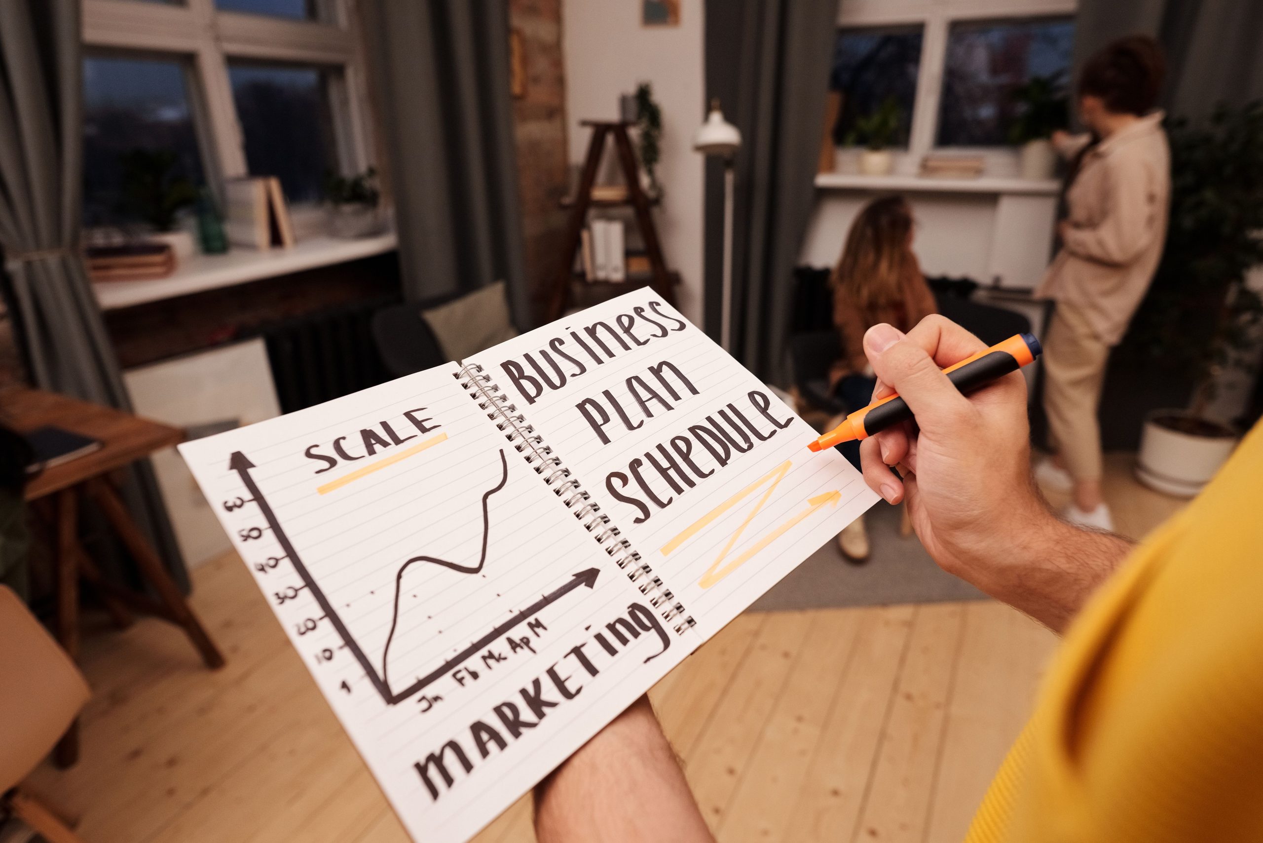 Person holding a notebook with planning details and graph for business strategy indoors.